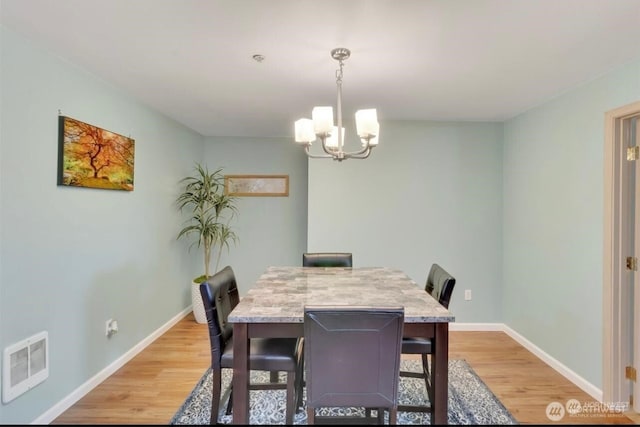 dining space featuring light wood-style flooring, a chandelier, and baseboards