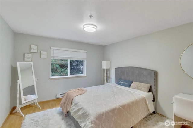 bedroom featuring wood finished floors, baseboards, and a baseboard heating unit