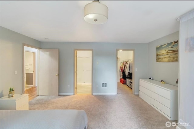 carpeted bedroom with a spacious closet, baseboards, and a closet