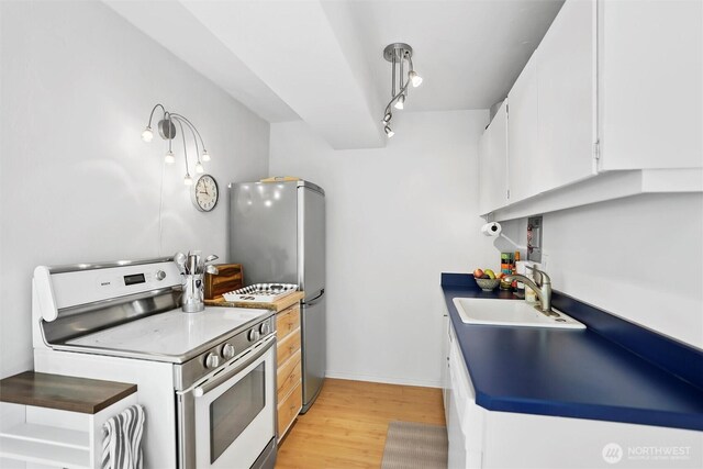 1200 Boylston Ave Unit 301, Seattle, WA 98101 - kitchen with white range with electric cooktop, white cabinets, light wood-type flooring, a sink, and baseboards