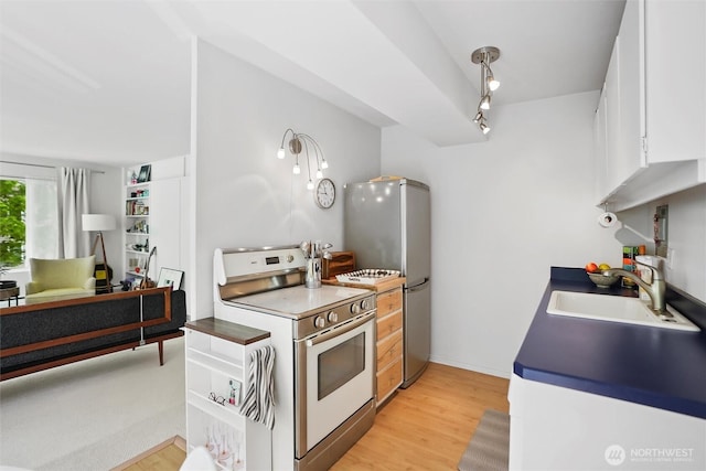 1200 Boylston Ave Unit 301, Seattle, WA 98101 - kitchen featuring white electric stove, a sink, light wood-type flooring, white cabinets, and freestanding refrigerator