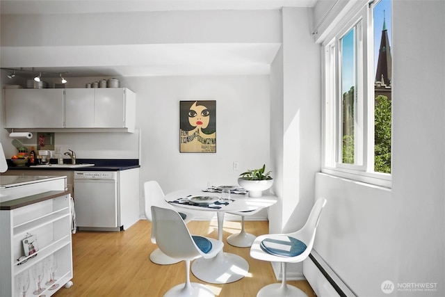 1200 Boylston Ave Unit 301, Seattle, WA 98101 - kitchen featuring dishwasher, light wood finished floors, dark countertops, a sink, and white cabinetry