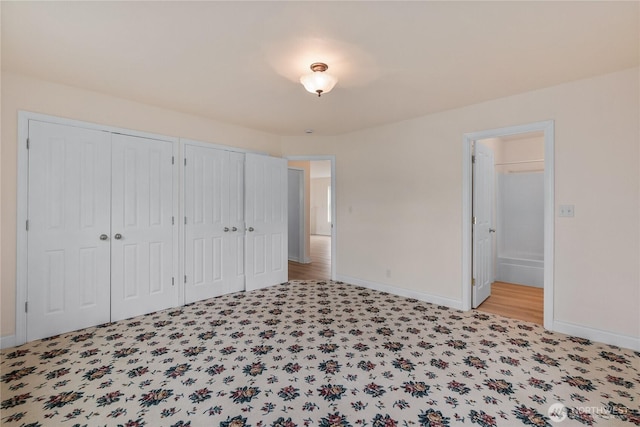 unfurnished bedroom featuring multiple closets, baseboards, and connected bathroom