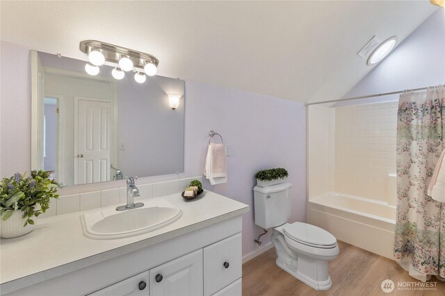 bathroom with toilet, wood finished floors, vanity, shower / bath combo with shower curtain, and vaulted ceiling