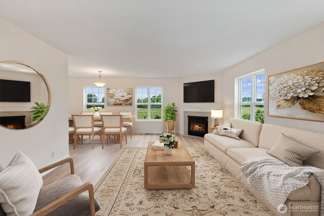 living area featuring a fireplace with flush hearth, light wood-style flooring, and baseboards