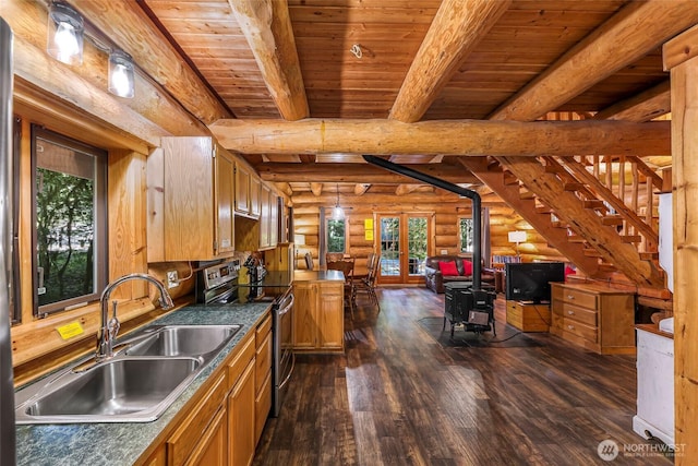 kitchen with electric range, rustic walls, a sink, dark wood-style flooring, and a wood stove