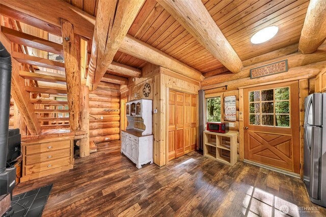 foyer entrance featuring wooden ceiling, beam ceiling, rustic walls, a wood stove, and dark wood finished floors