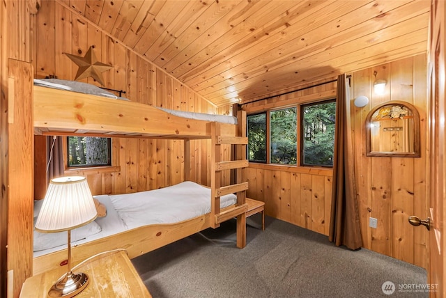 carpeted bedroom featuring wooden walls, vaulted ceiling, and wood ceiling