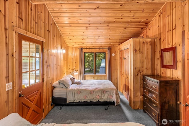 carpeted bedroom featuring wooden walls and wooden ceiling