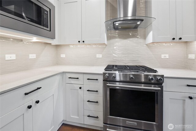 1086 Collier Pl SW, Issaquah, WA 98027 - kitchen featuring appliances with stainless steel finishes, wall chimney range hood, backsplash, and white cabinetry