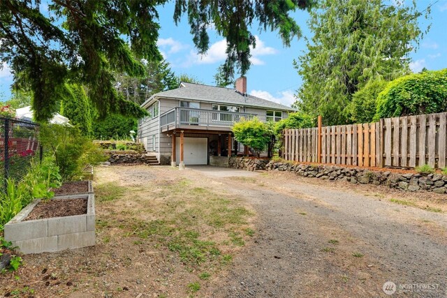 414 W Wyandotte Ave, Shelton, WA 98584 - view of front of home featuring dirt driveway, a chimney, an attached garage, a garden, and a deck