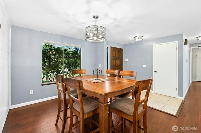 dining area with hardwood / wood-style floors, a chandelier, and baseboards