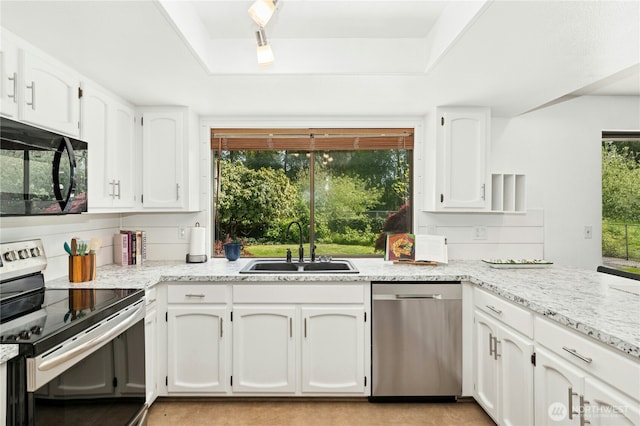 kitchen featuring stainless steel appliances, a sink, a raised ceiling, and white cabinets