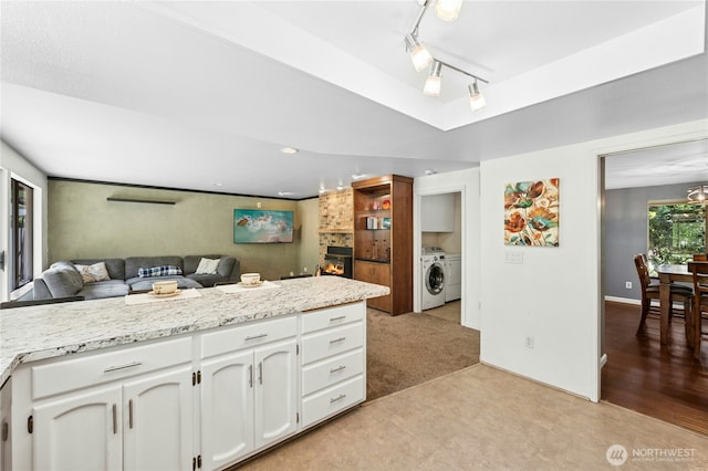 kitchen featuring washing machine and clothes dryer, white cabinetry, open floor plan, light countertops, and a raised ceiling