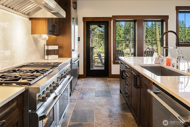 350 Kings Ct, Cle Elum, WA 98922 - kitchen with appliances with stainless steel finishes, wall chimney exhaust hood, stone tile flooring, a sink, and dark brown cabinets