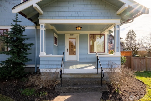 entrance to property with a porch and fence