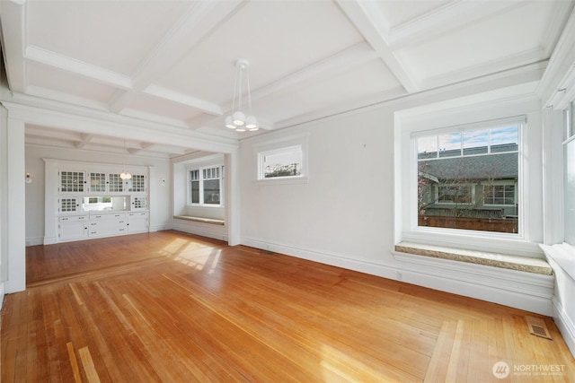 unfurnished dining area featuring coffered ceiling, baseboards, healthy amount of natural light, and beam ceiling