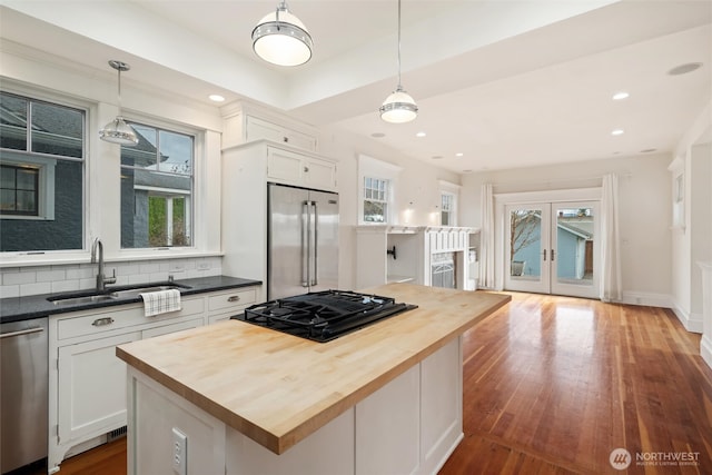 kitchen featuring appliances with stainless steel finishes, butcher block counters, a sink, healthy amount of natural light, and recessed lighting