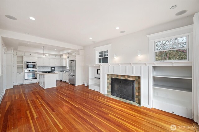 unfurnished living room with a fireplace with flush hearth, dark wood finished floors, and recessed lighting