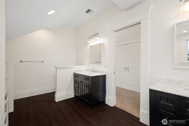full bath featuring wood finished floors, baseboards, lofted ceiling, two vanities, and recessed lighting
