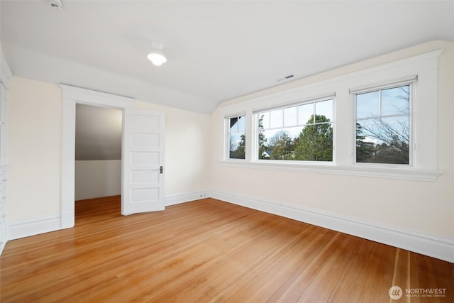 unfurnished bedroom featuring vaulted ceiling, light wood finished floors, and baseboards