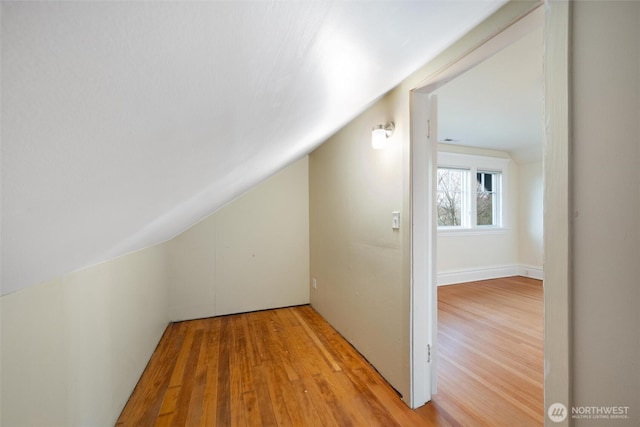 additional living space featuring lofted ceiling and light wood-style flooring