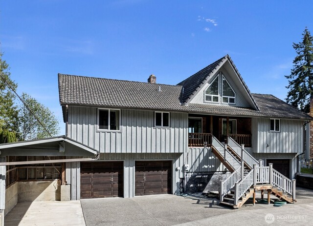 view of front of property featuring a garage, stairs, covered porch, a chimney, and concrete driveway