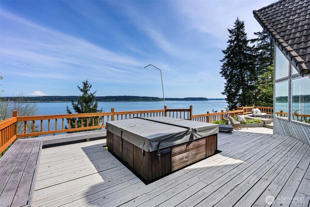 wooden deck with a hot tub and a water view