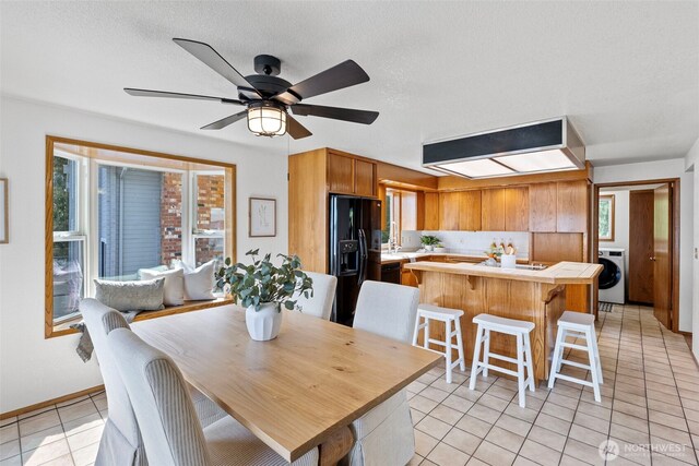dining area featuring washer / clothes dryer, light tile patterned floors, and a ceiling fan