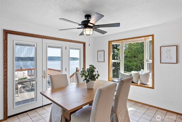 dining space with light tile patterned floors, a water view, a textured ceiling, a ceiling fan, and french doors