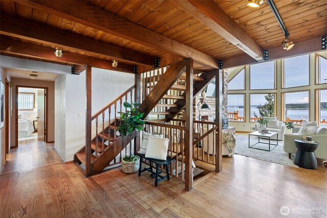 stairs featuring beamed ceiling, wood finished floors, wood ceiling, and a water view
