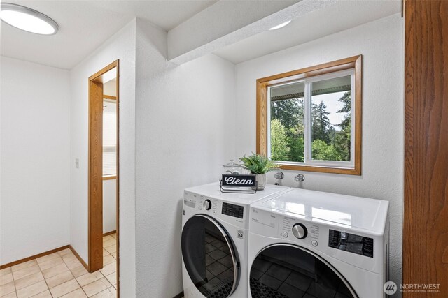 laundry room featuring separate washer and dryer, baseboards, and light tile patterned floors