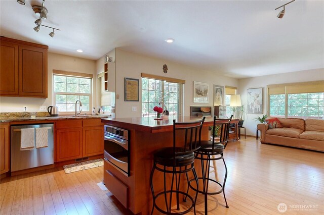 18 Blue Creek Rd, Walla Walla, WA 99362 - kitchen with stainless steel appliances, a sink, rail lighting, a kitchen bar, and light wood-style floors