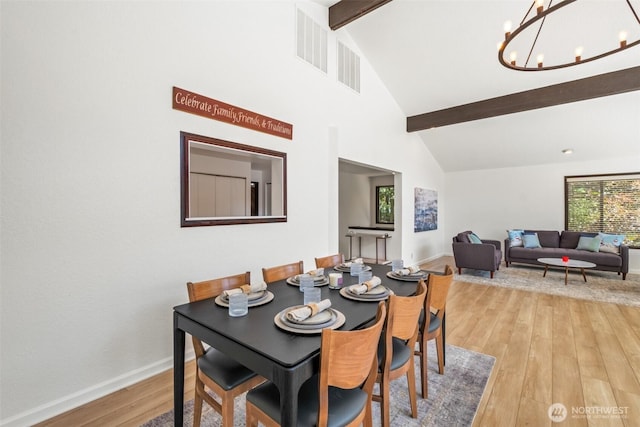 dining space with beamed ceiling, light wood-type flooring, a chandelier, baseboards, and high vaulted ceiling