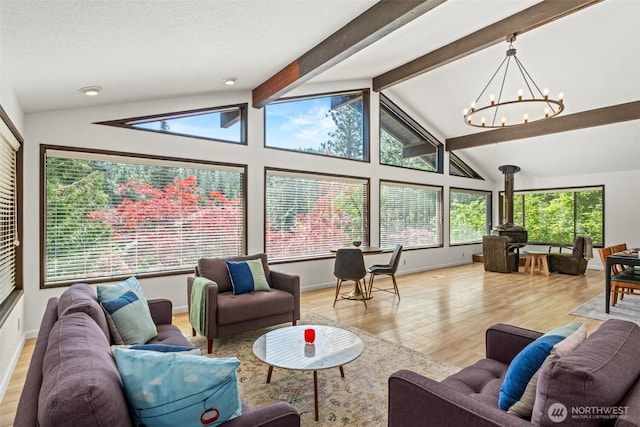 living area with light wood-type flooring, a chandelier, baseboards, and a wood stove