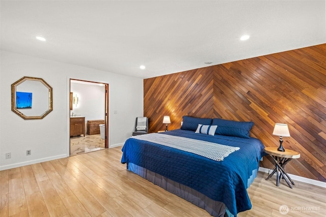 bedroom with wooden walls, baseboards, recessed lighting, light wood finished floors, and ensuite bathroom