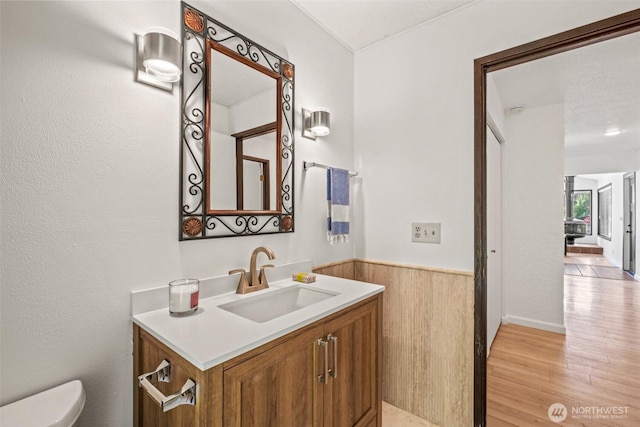 half bathroom with toilet, wood finished floors, and vanity