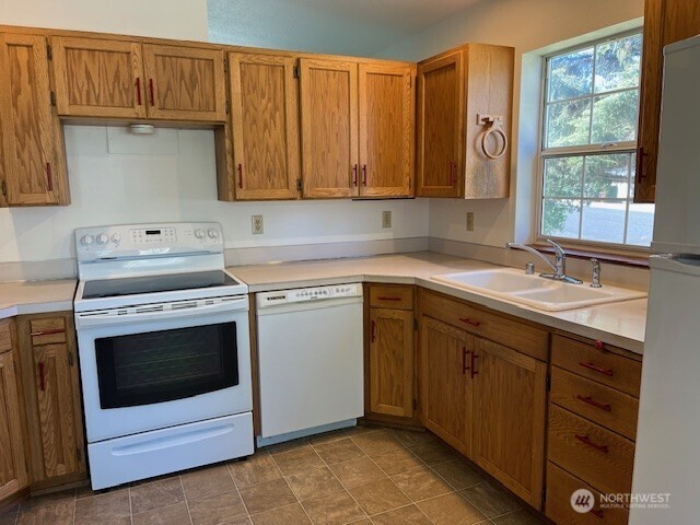 434 SE Stanford Pl, College Place, WA 99324 - kitchen with white appliances, a sink, light countertops, and brown cabinets
