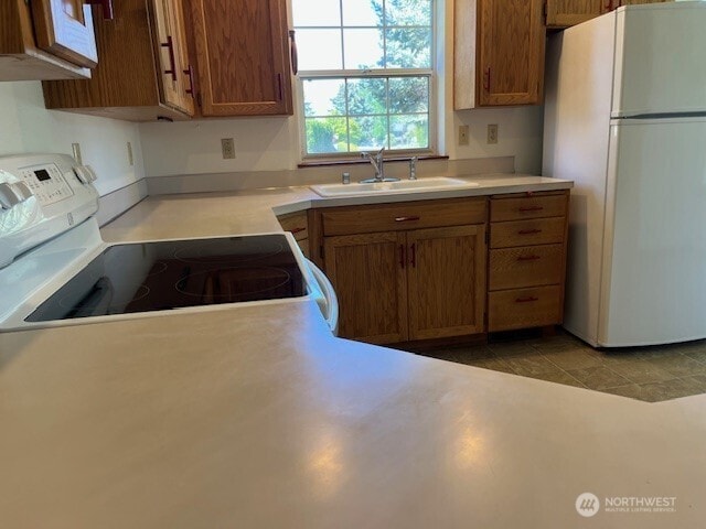 434 SE Stanford Pl, College Place, WA 99324 - kitchen with white appliances, a sink, brown cabinetry, and light countertops
