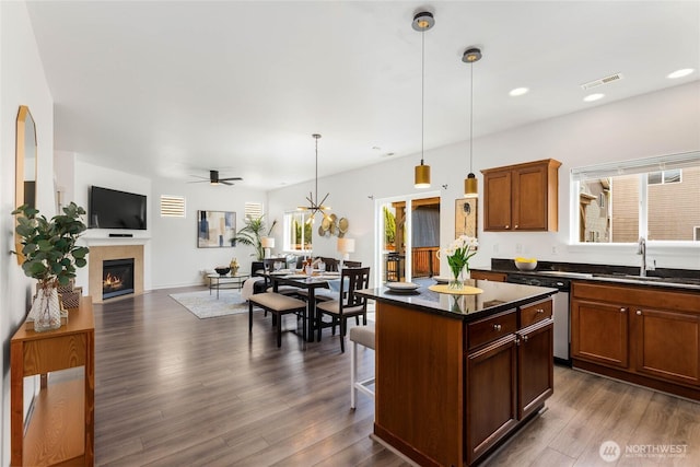 kitchen featuring a sink, dishwasher, ceiling fan, a tiled fireplace, and open floor plan