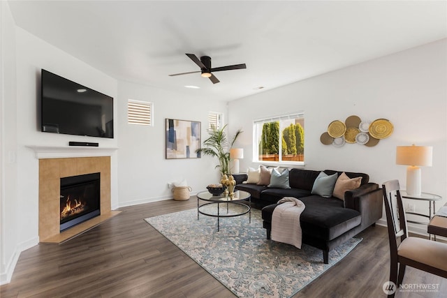 living room featuring ceiling fan, dark wood-style flooring, a fireplace, and baseboards