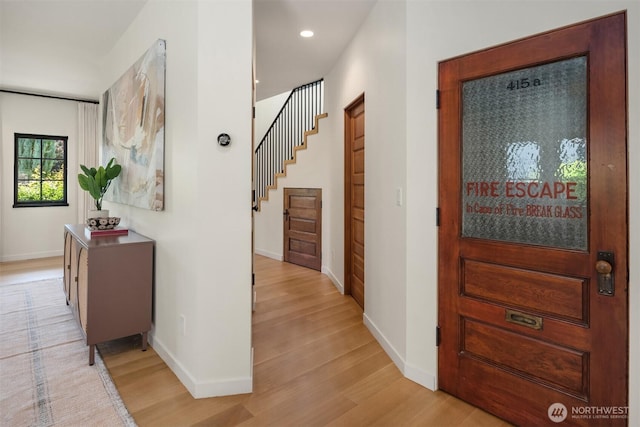 hall featuring light wood-type flooring, baseboards, stairs, and recessed lighting
