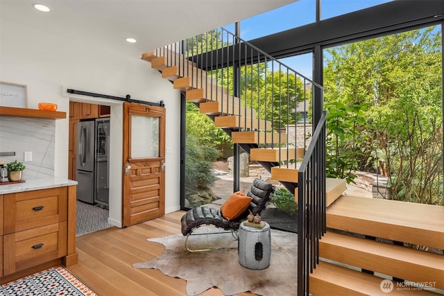 stairway featuring wood finished floors, a barn door, and recessed lighting