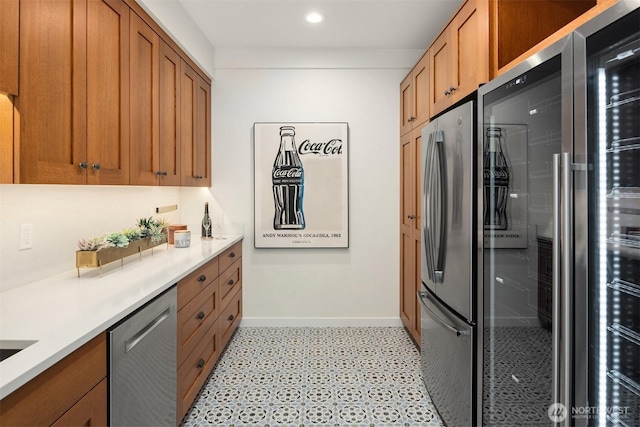 kitchen featuring appliances with stainless steel finishes, baseboards, brown cabinetry, light countertops, and recessed lighting