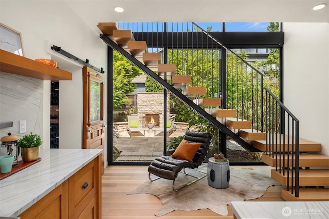 doorway with stairs, light wood finished floors, recessed lighting, and a barn door