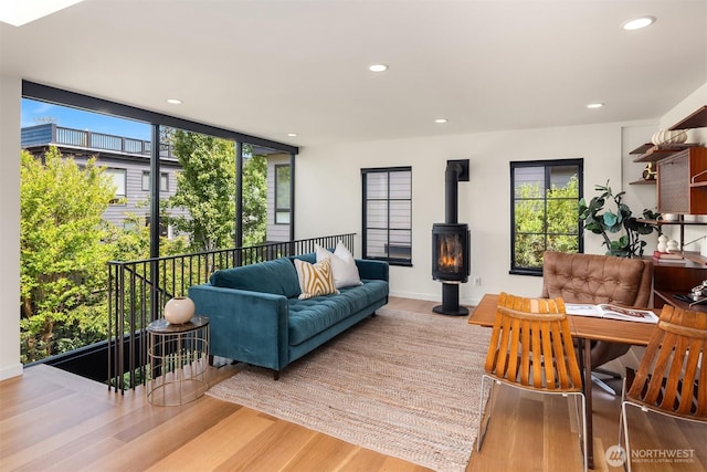 living area with wood finished floors, a wood stove, healthy amount of natural light, recessed lighting, and a wall of windows