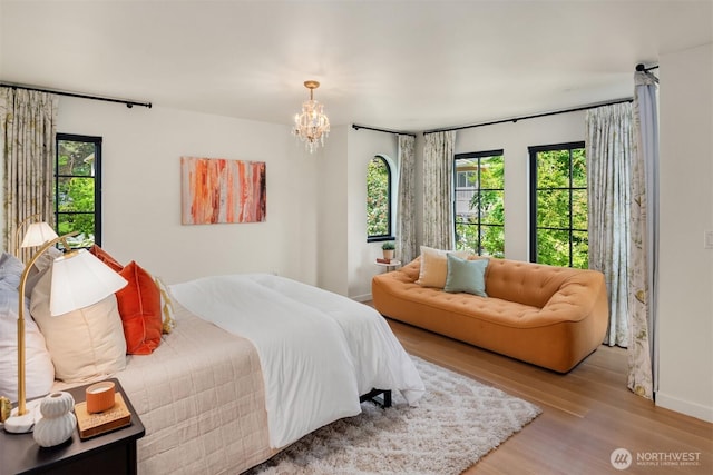 bedroom with a chandelier, wood finished floors, and baseboards