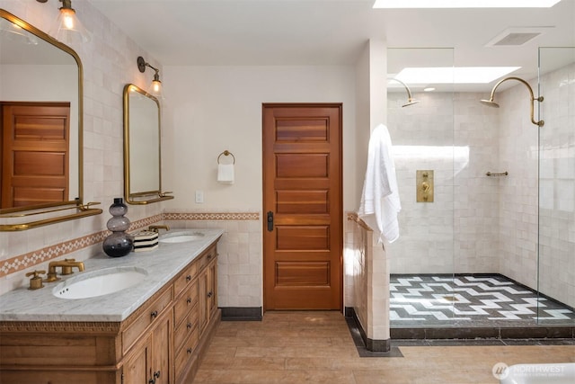 full bath with tile walls, a shower stall, double vanity, wood finished floors, and a wainscoted wall