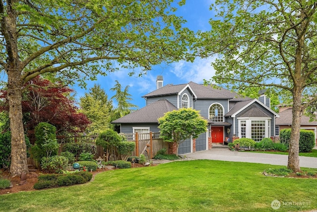 traditional-style house with driveway, a chimney, a shingled roof, and an attached garage