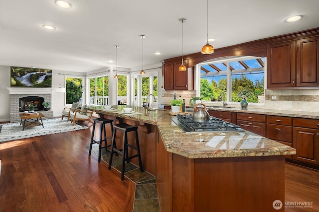 kitchen with stainless steel gas cooktop, open floor plan, tasteful backsplash, a sink, and recessed lighting
